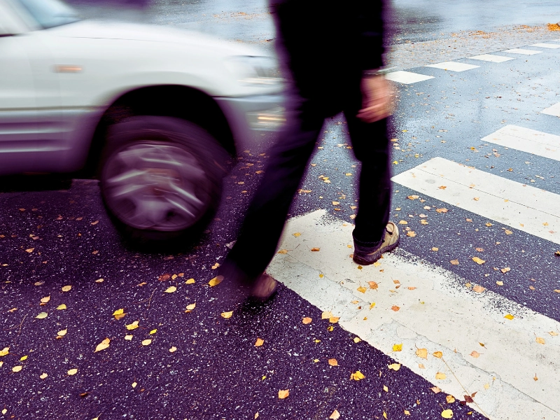 Man on pedestrian crossing in danger of being hit by car.
