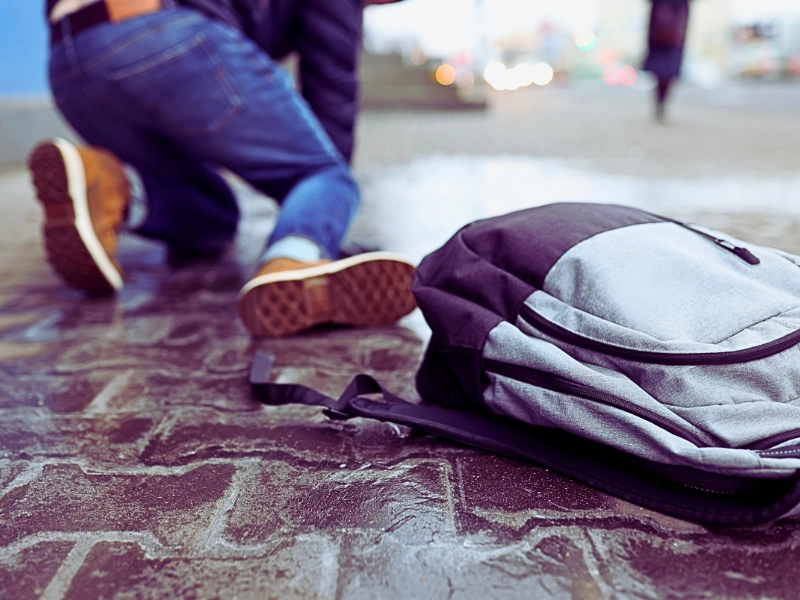 Man with backpack felling on slippery sidewalk.