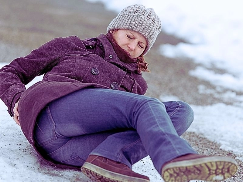 Young woman has an accident on a icy way with black ice.