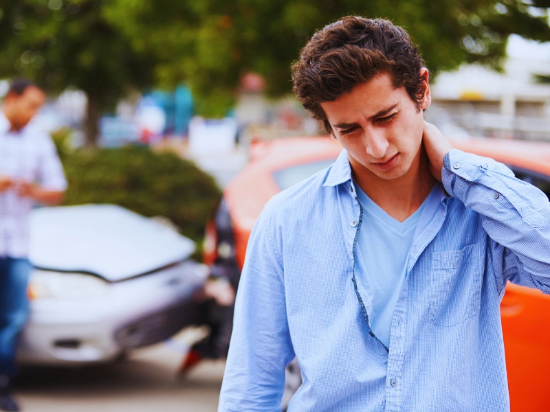 young man rubbing injured neck, representing a motor vehicle accident injury