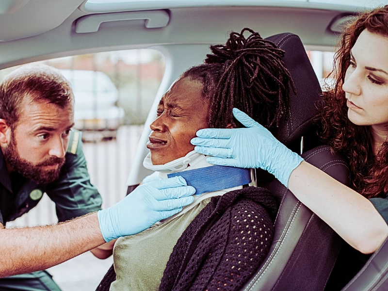 EMTs putting neck brace on injured woman in car