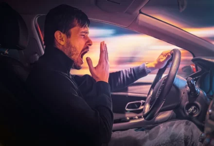 Young sleepy man is yawning and driving car at night. drowsy driving