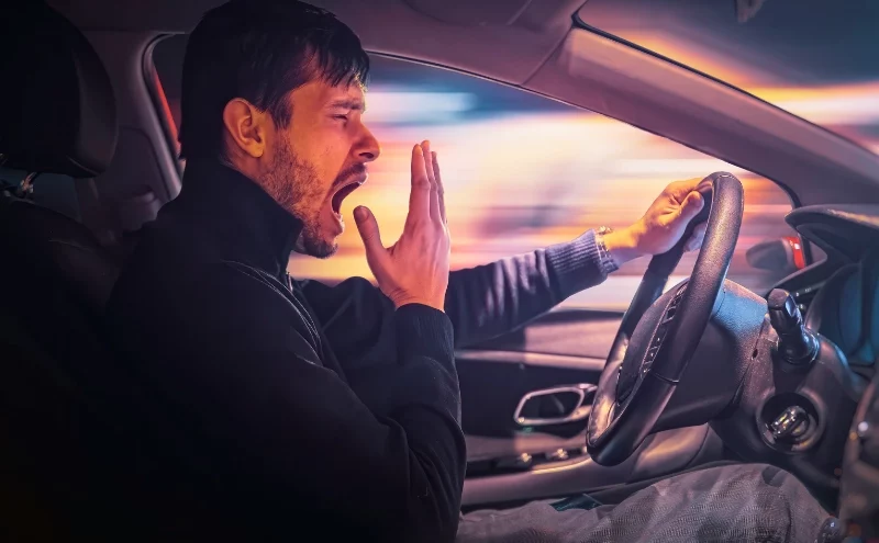 The Dangers of Drowsy Driving: Can Fatigue Be Considered Negligence? 1 Young sleepy man is yawning and driving car at night. drowsy driving