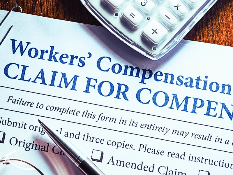 Workers' Compensation form with pen and glasses. retaliation for filing a workers' comp claim