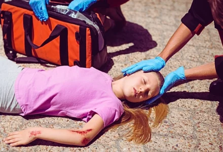 Paramedics examining injured girl on street. Your Child Is Injured in a Car Accident