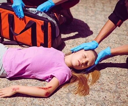 Paramedics examining injured girl on street. Your Child Is Injured in a Car Accident