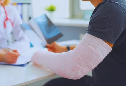 Doctor conducts medical consultation with patient with cast on arm. Aggravated a Pre-Existing Injury
