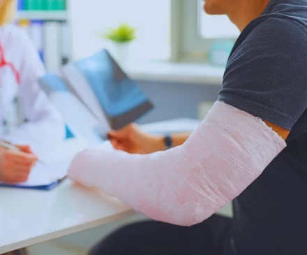 Doctor conducts medical consultation with patient with cast on arm. Aggravated a Pre-Existing Injury