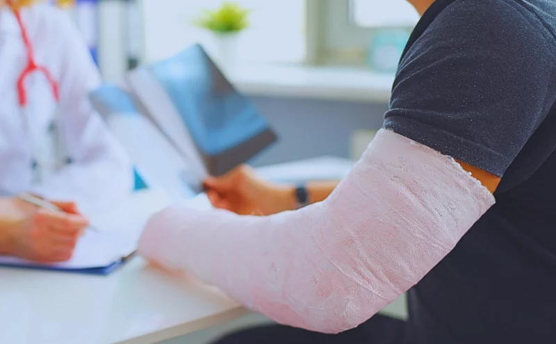Doctor conducts medical consultation with patient with cast on arm. Aggravated a Pre-Existing Injury