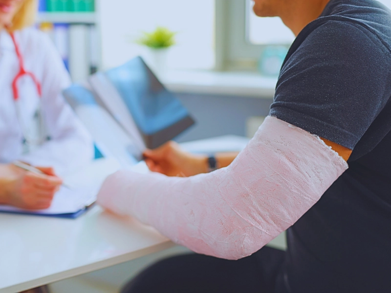 Doctor conducts medical consultation with patient with cast on arm. Aggravated a Pre-Existing Injury