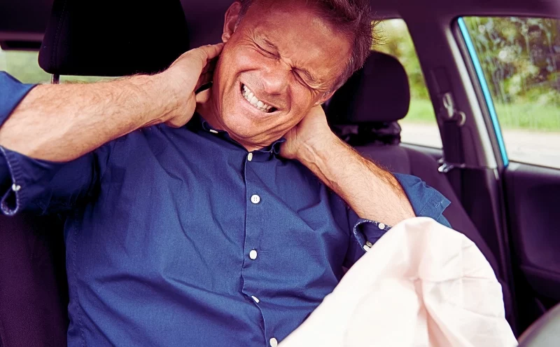 Car Accidents While On the Job: Do You File Workers’ Comp or a Personal Injury Claim? 1 Male Motorist With Whiplash Injury In Car Crash With Airbag Deployed. Car Accidents While On the Job