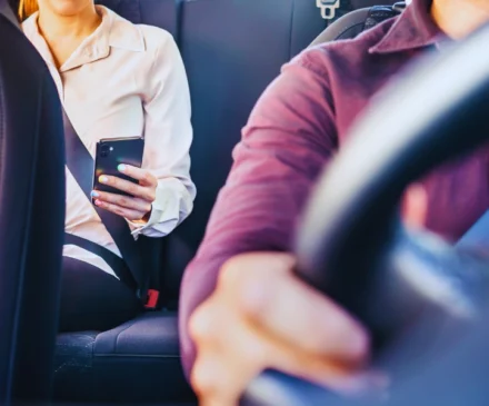 Test New 15 Phone in car or taxi. Passenger woman using cellphone in back seat of cab.