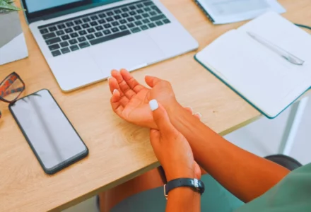 Wrist, arm and pain by laptop desk of employee worker suffering from carpal tunnel. Repetitive Stress Injuries