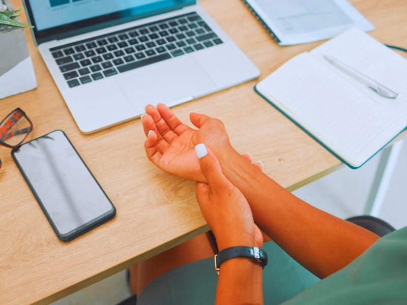 Wrist, arm and pain by laptop desk of employee worker suffering from carpal tunnel. Repetitive Stress Injuries