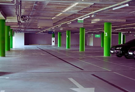 an underground parking garage with overhead lights and exit signs hanging from the ceiling. Hit by a Car in a Naperville Parking Lot