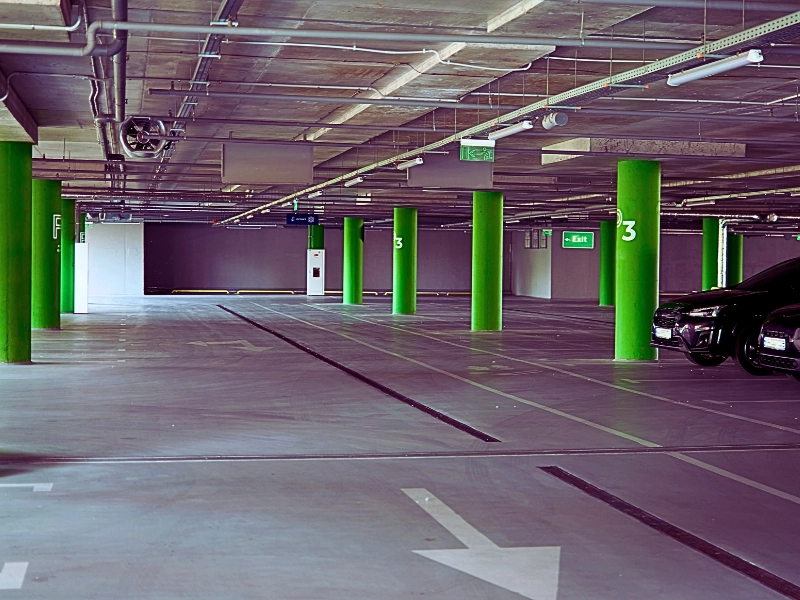 an underground parking garage with overhead lights and exit signs hanging from the ceiling. Hit by a Car in a Naperville Parking Lot