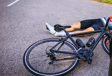cyclist lying on the road next to a fallen bicycle, indicating a serious hit-and-run accident.