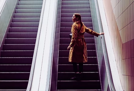 a woman standing alone on an escalator going up inside a building. Injured on an Elevator