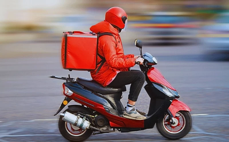 Who’s Liable After an UberEats, DoorDash, or Grubhub Delivery Driver Accident in Illinois? 1 a delivery rider wearing a red helmet and jacket, riding a red scooter on a city street. Delivery Driver Accident