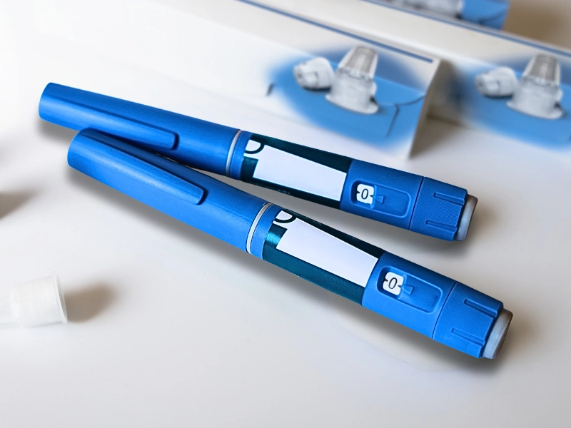 Two blue injection pens, likely for medication, placed on a white surface.