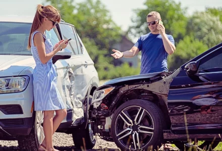 Two drivers assess damage while calling after crash. if the at-fault driver doesn't have enough insurance