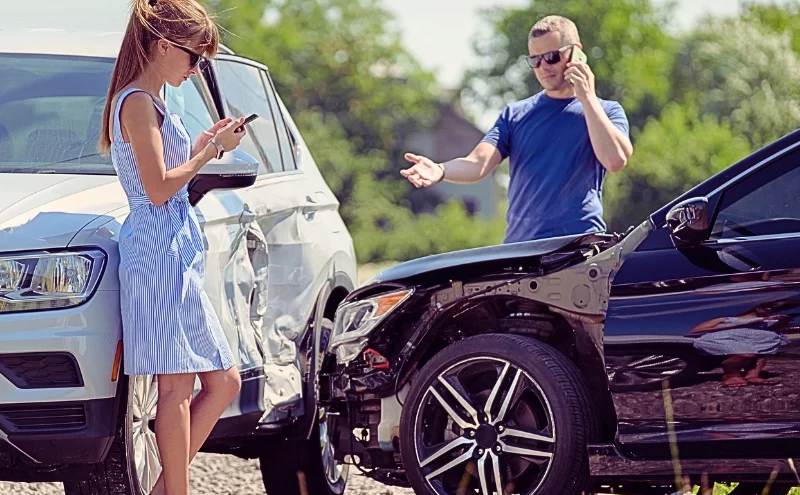 Two drivers assess damage while calling after crash. if the at-fault driver doesn't have enough insurance