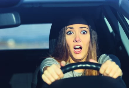 Terrified woman clutching steering wheel while driving a car. Responsible for a Teen Driver’s Car Accident