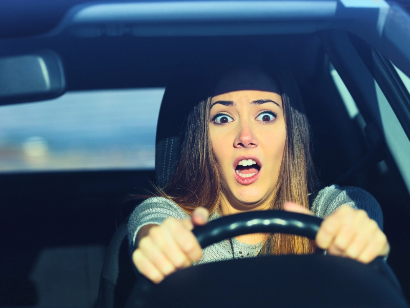 Terrified woman clutching steering wheel while driving a car. Responsible for a Teen Driver’s Car Accident