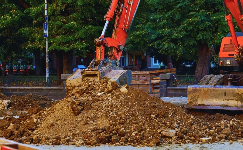 Edwardsville Jobsite Injury Highlights Hidden Hazards in Public Works Projects 1 An orange excavator bucket moving a pile of dirt.