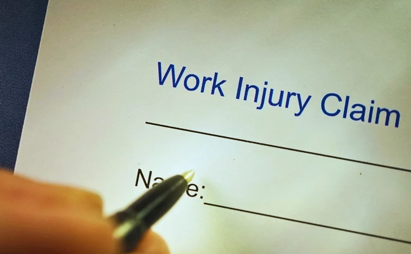 Close up of person signing a work injury claim. Independent contractors get workers' compensation