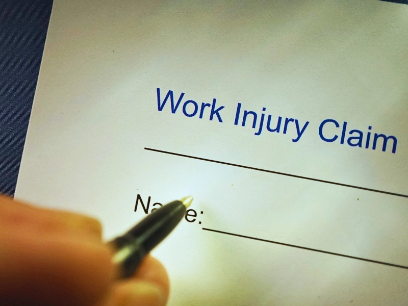 Close up of person signing a work injury claim. Independent contractors get workers' compensation