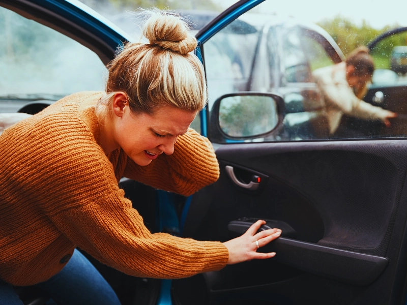 Woman holding her neck in pain while exiting car. Passenger Sue for Injuries