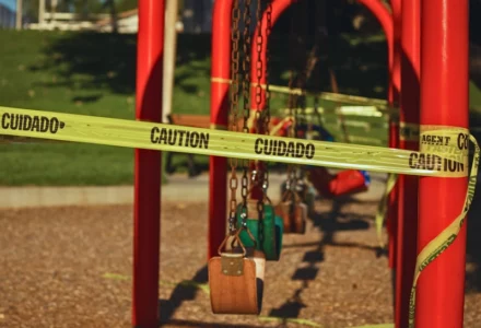 Yellow caution tape wrapped around a closed playground swing. Unsafe Playground Equipment