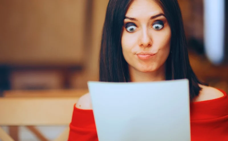 Should I Accept the First Settlement Offer After a Car Accident? 1 Surprised woman looking at a paper with wide eyes. first settlement offer after a car accident