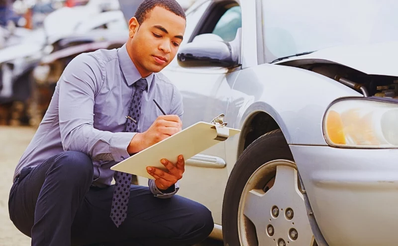 What Happens If the Insurance Company Denies Your Car Accident Claim in Illinois? 1 Insurance adjuster inspecting and writing on clipboard near damaged car. insurance company denies your car accident claim