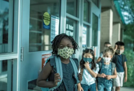 Young students wearing face masks lining up outside school. school pickup line accidents