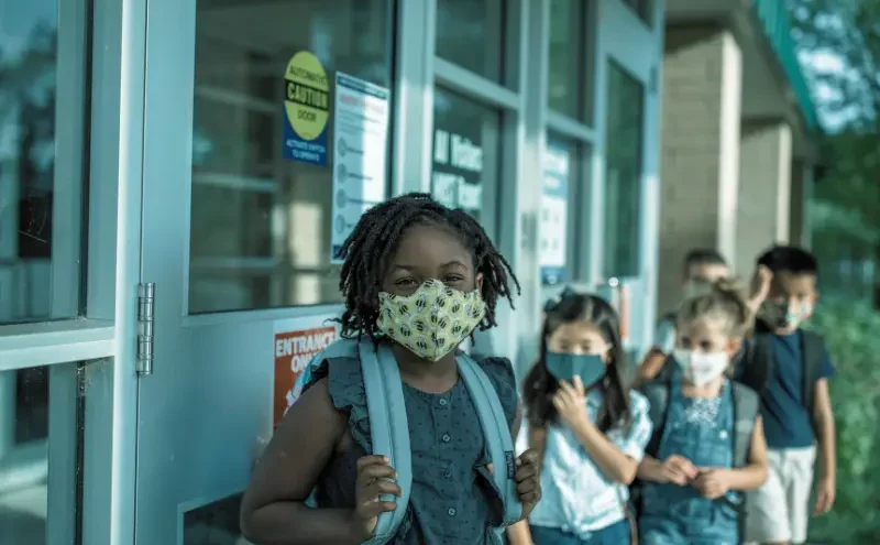Young students wearing face masks lining up outside school. school pickup line accidents