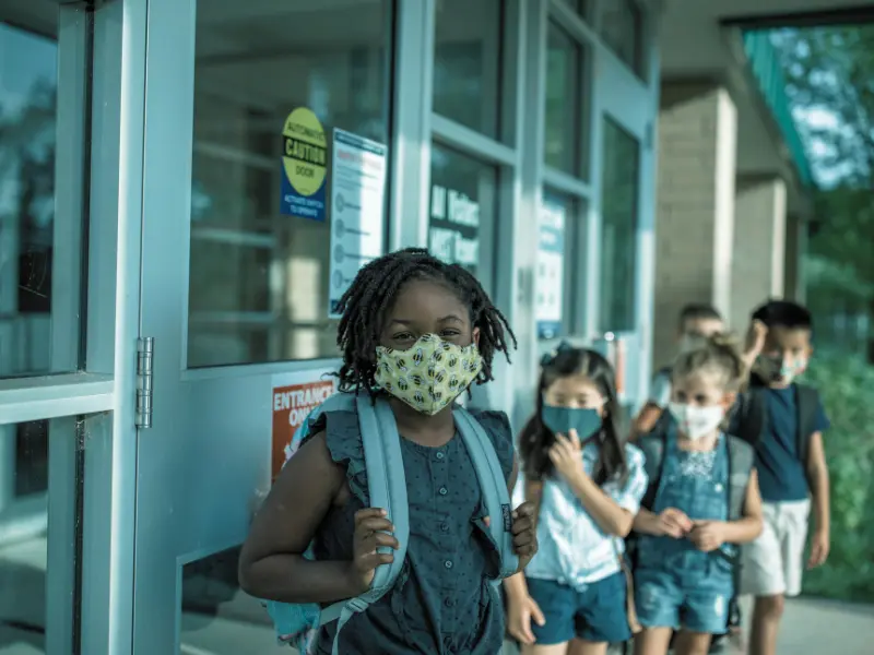 Young students wearing face masks lining up outside school. school pickup line accidents