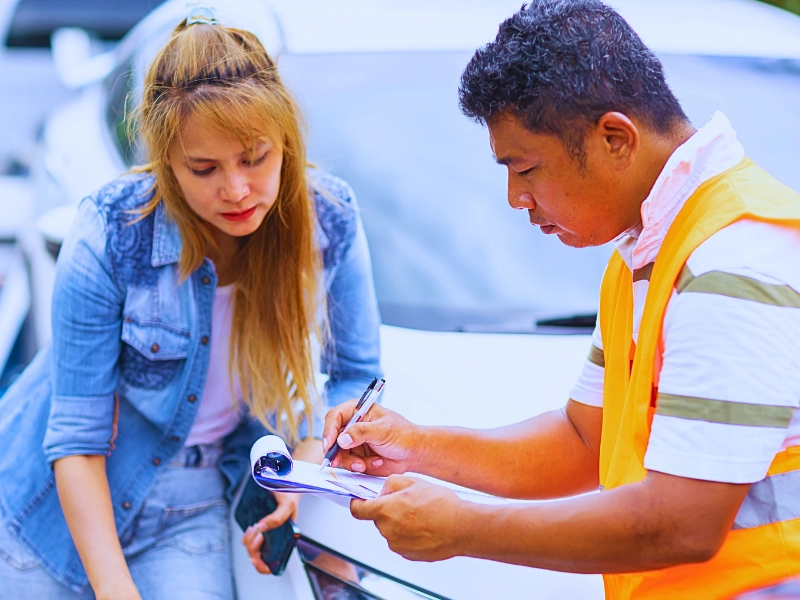 Man in safety vest writing on clipboard next to woman.