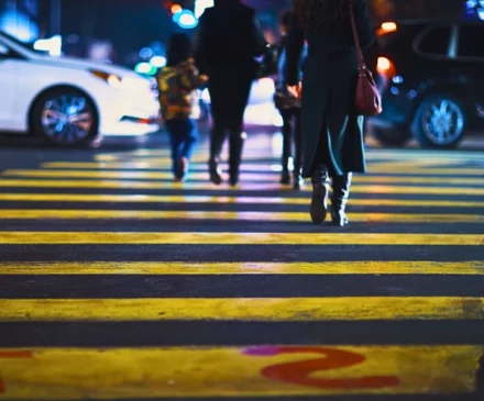 Pedestrians walking across a yellow crosswalk on a city street. downtown Naperville