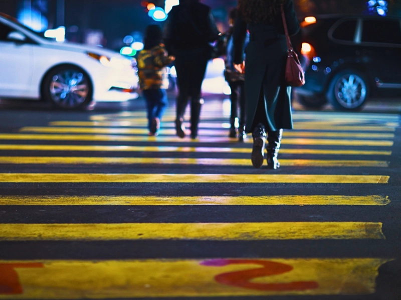 Pedestrians walking across a yellow crosswalk on a city street. downtown Naperville