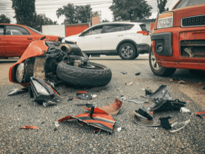 An accident between a motorcycle and a car. Pieces of the motorcycle on the ground.